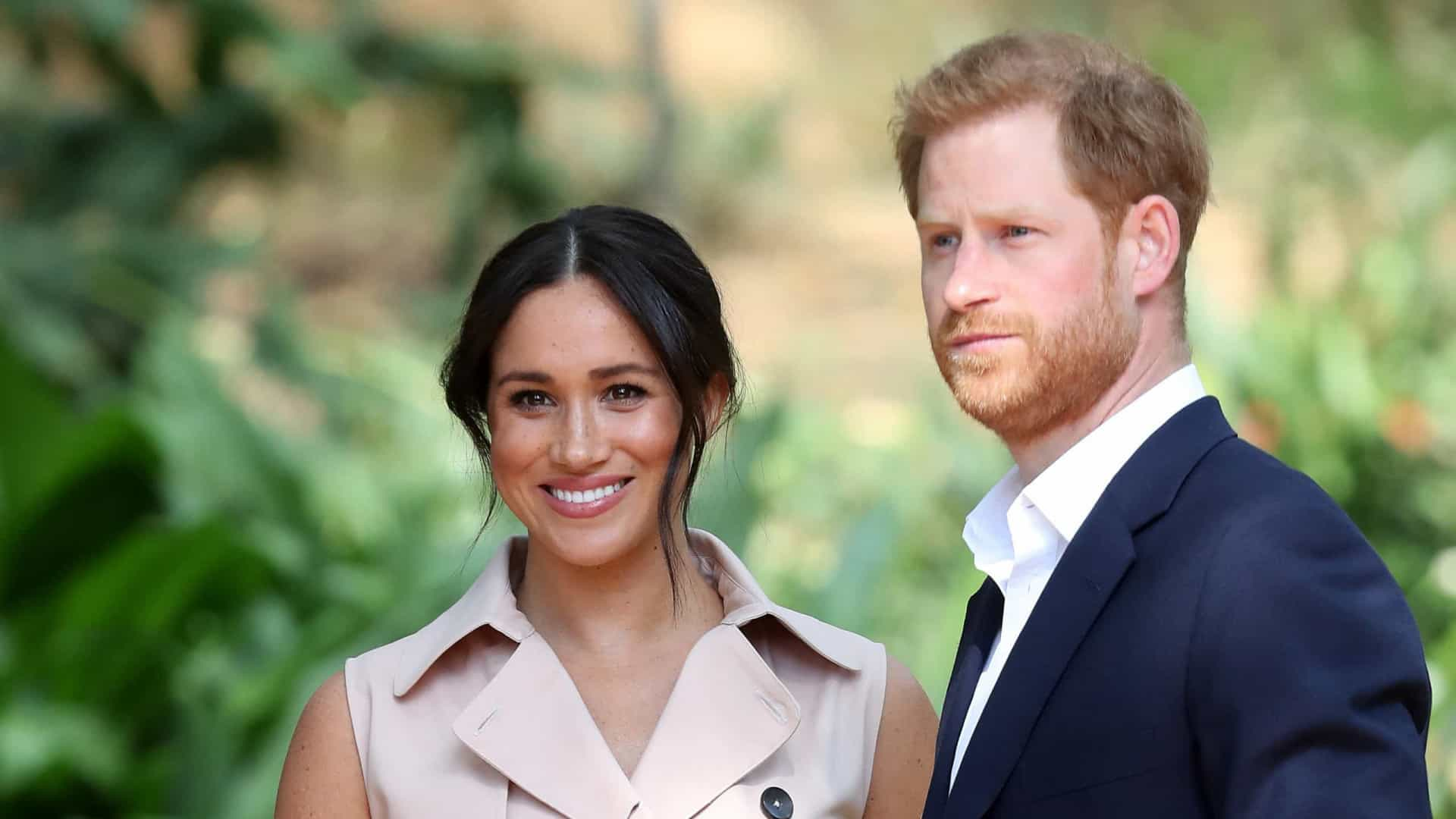 Casal do Príncipe Harry e Megan Markle juntos, com ela sorrindo para a foto